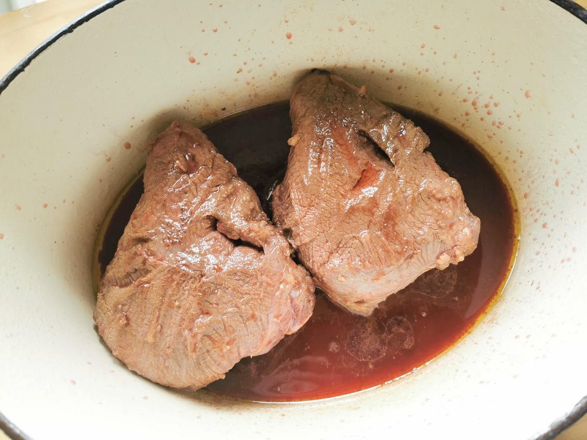 Beef cheeks cooking in red wine in Dutch oven.