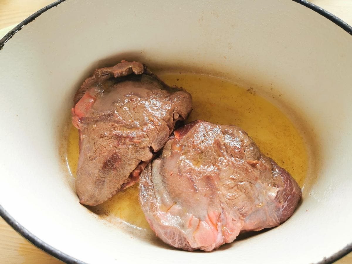 Seared beef cheeks in Dutch oven with olive oil.