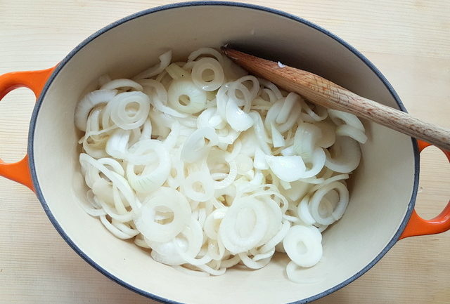 sliced white onions cooking in Dutch oven