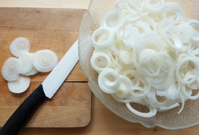 sliced white onions in a glass bowl