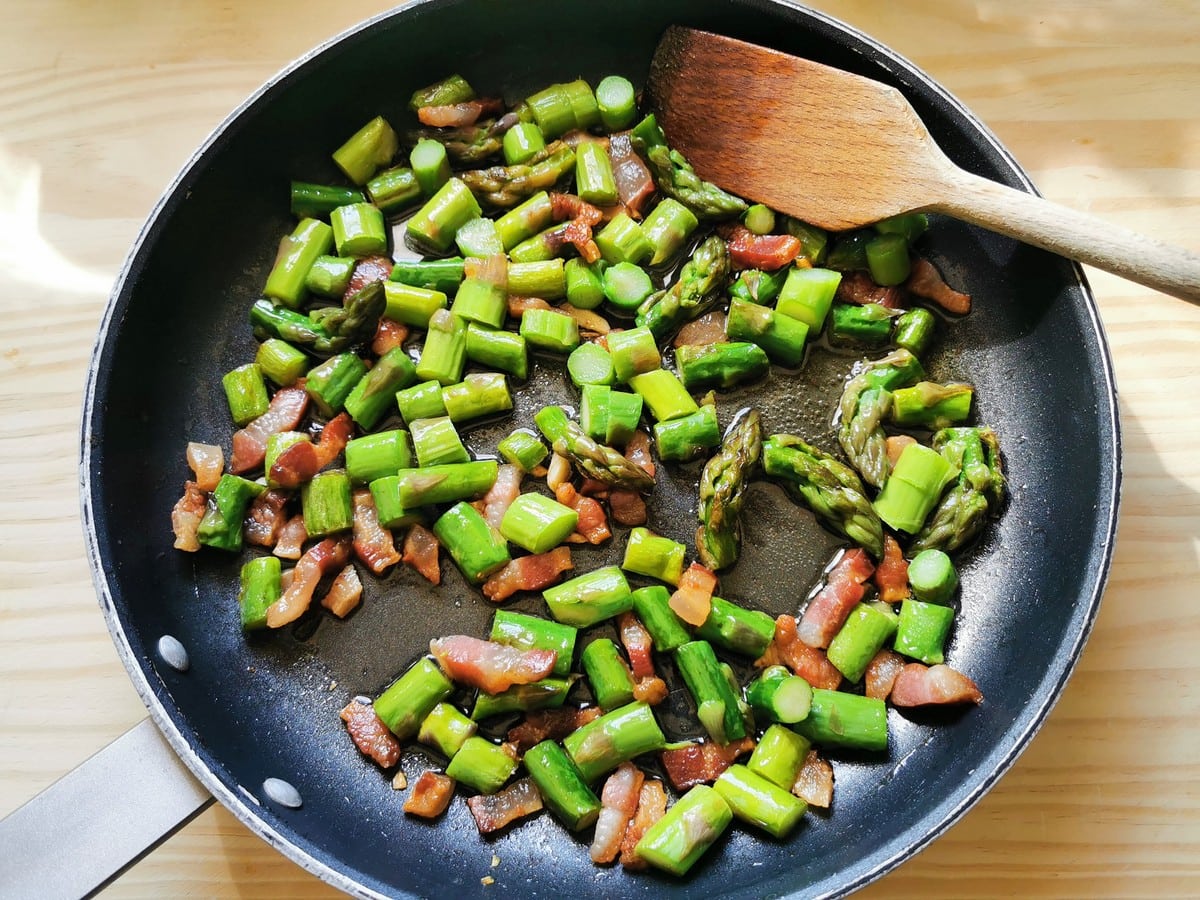 pieces of asparagus in skillet with cooked guanciale