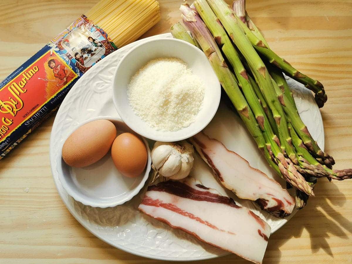 ingredients for spaghetti carbonara with asparagus on white plate