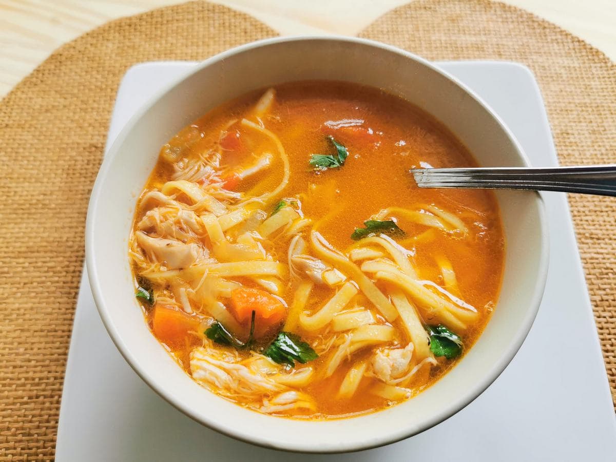 Italian chciken noodle soup in white bowl.