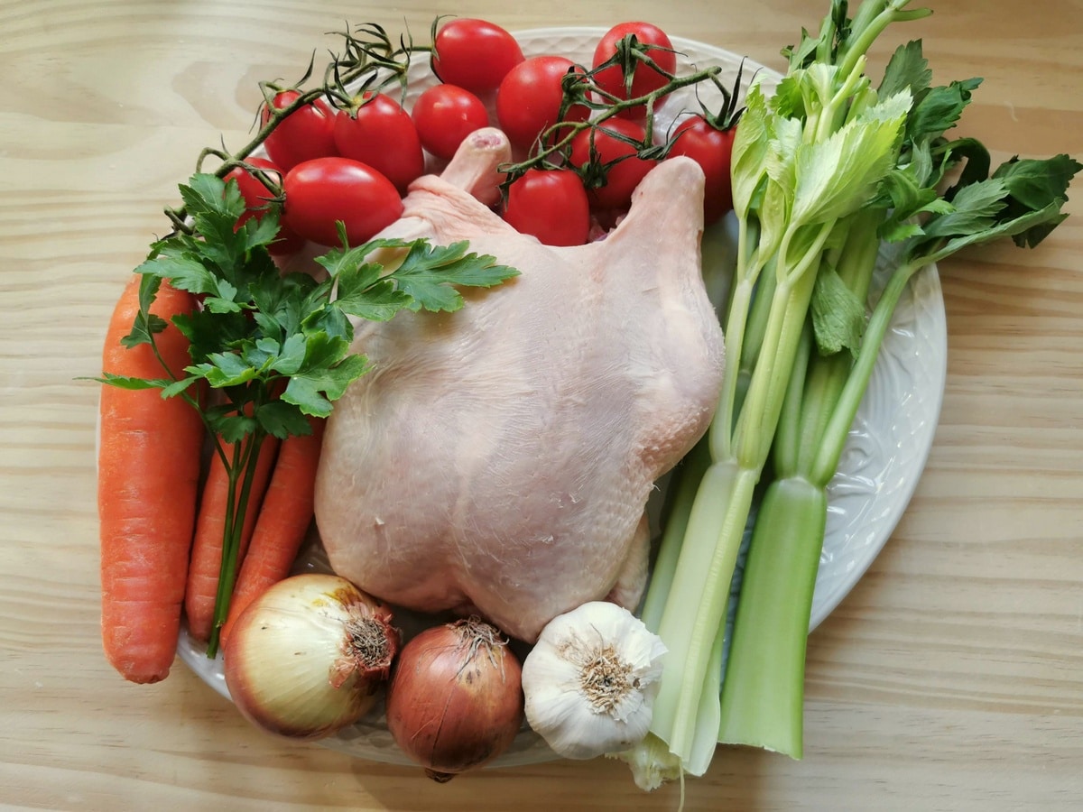 ingredients for chicken broth and chicken noodle soup on white plate