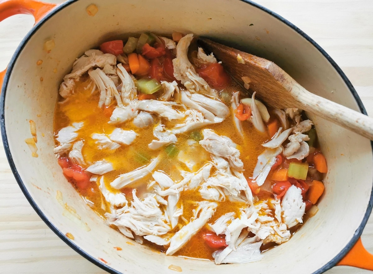 chicken meat and broth added to Dutch oven with tomatoes and vegetables