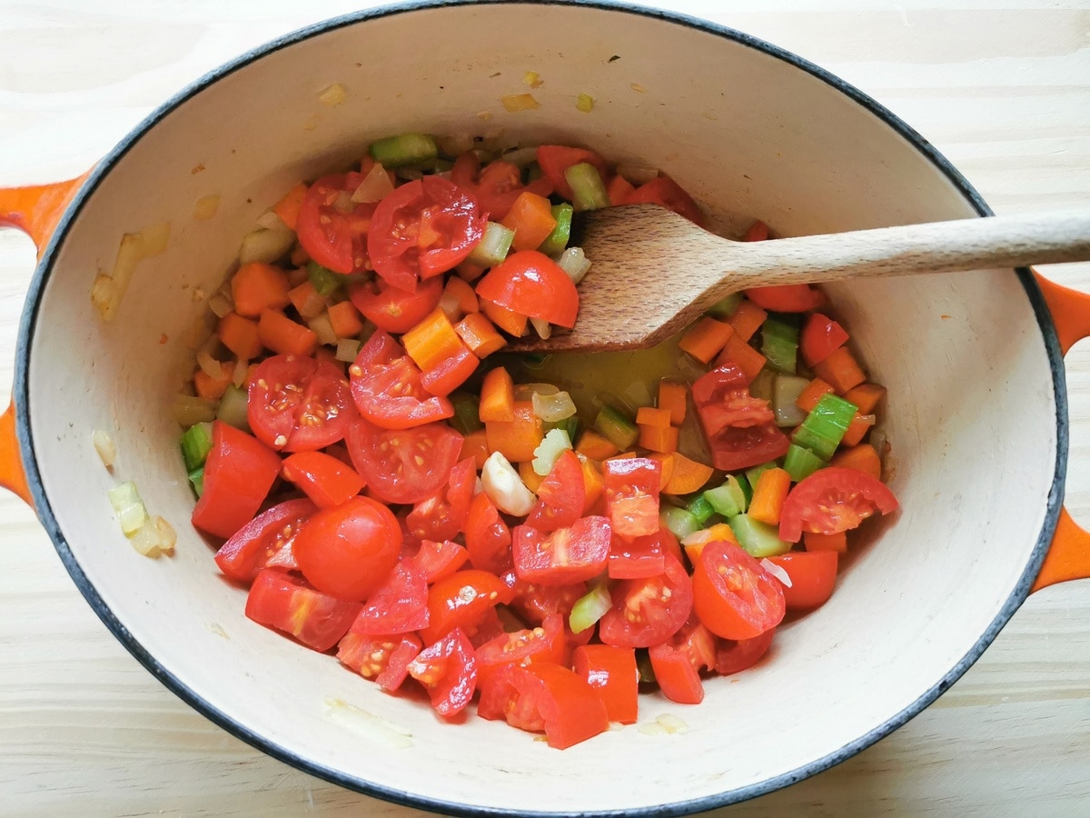 fresh tomatoes added to vegetables in Dutch oven.