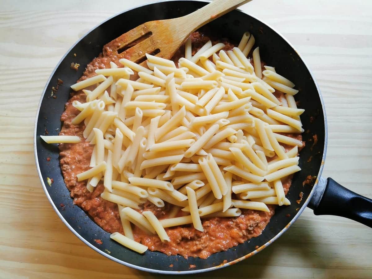 Cooked penne in pan with creamy beef ragu.