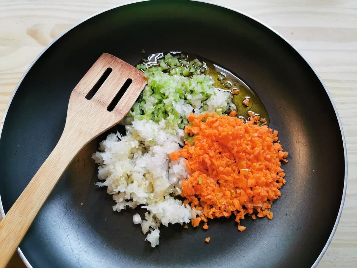 Finely chopped onion, carrot and celery in frying pan with olive oil.