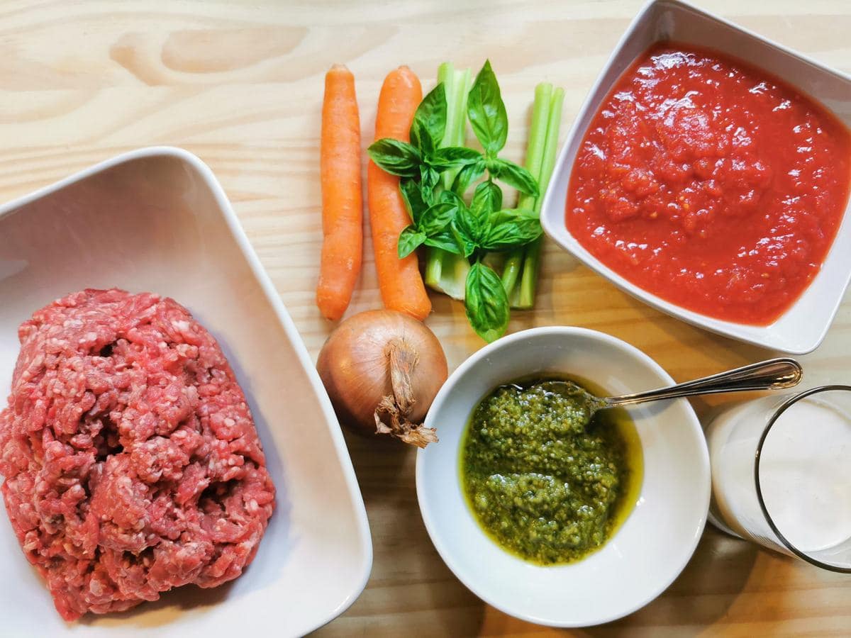 ingredients for creamy beef ragu on wood work surface.