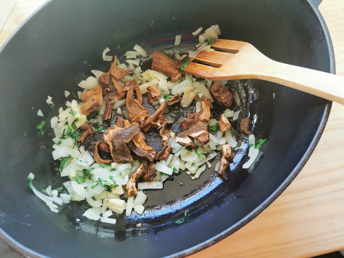 Soaked porcini mushrooms in Dutch oven with chopped onion, garlic and celery.