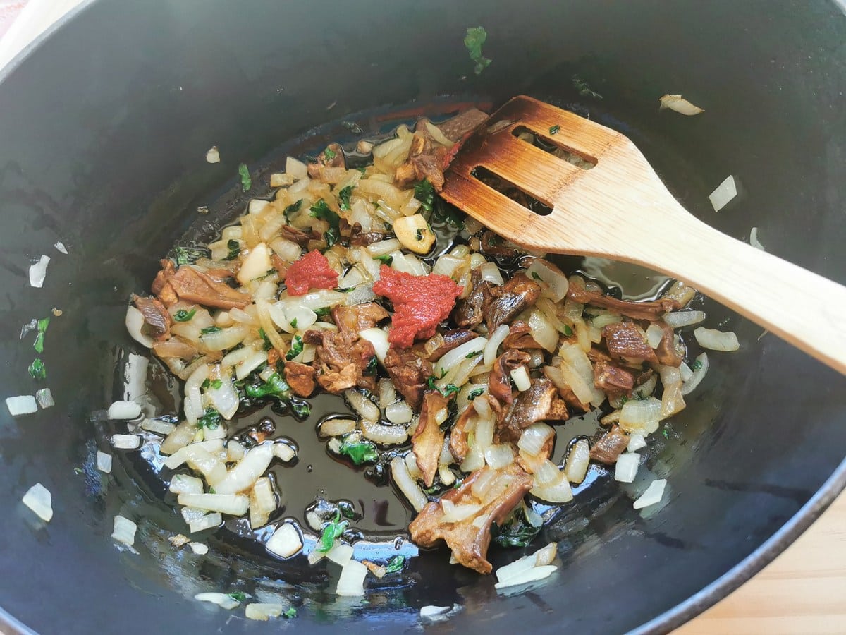 Tomato paste added to Dutch oven with mushrooms, onion, garlic and parsley.