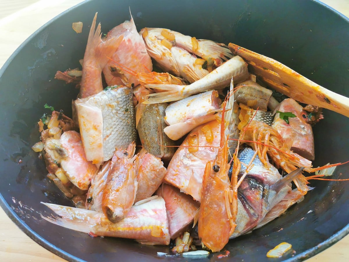 Pieces of fish and prawn heads in Dutch oven.