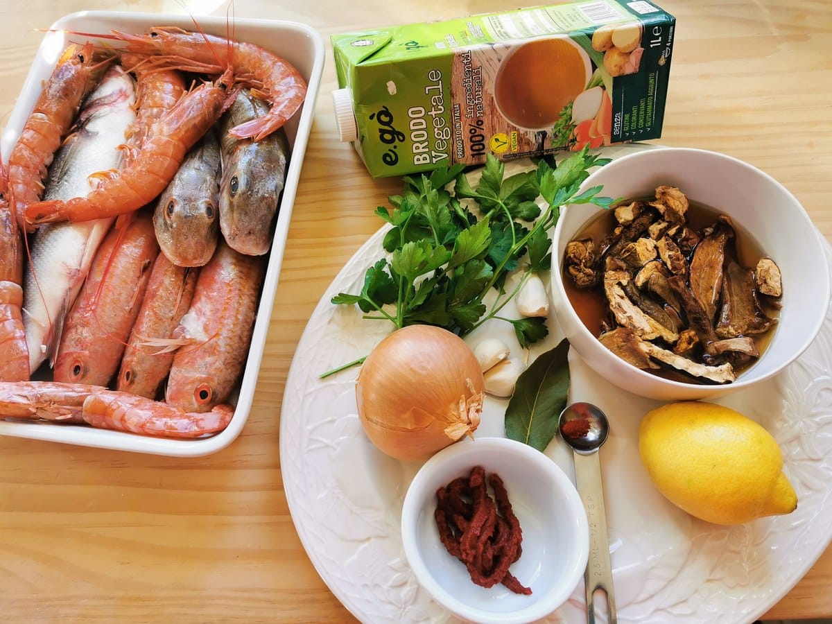 All the ingredients in this fish soup on a wood work surface.