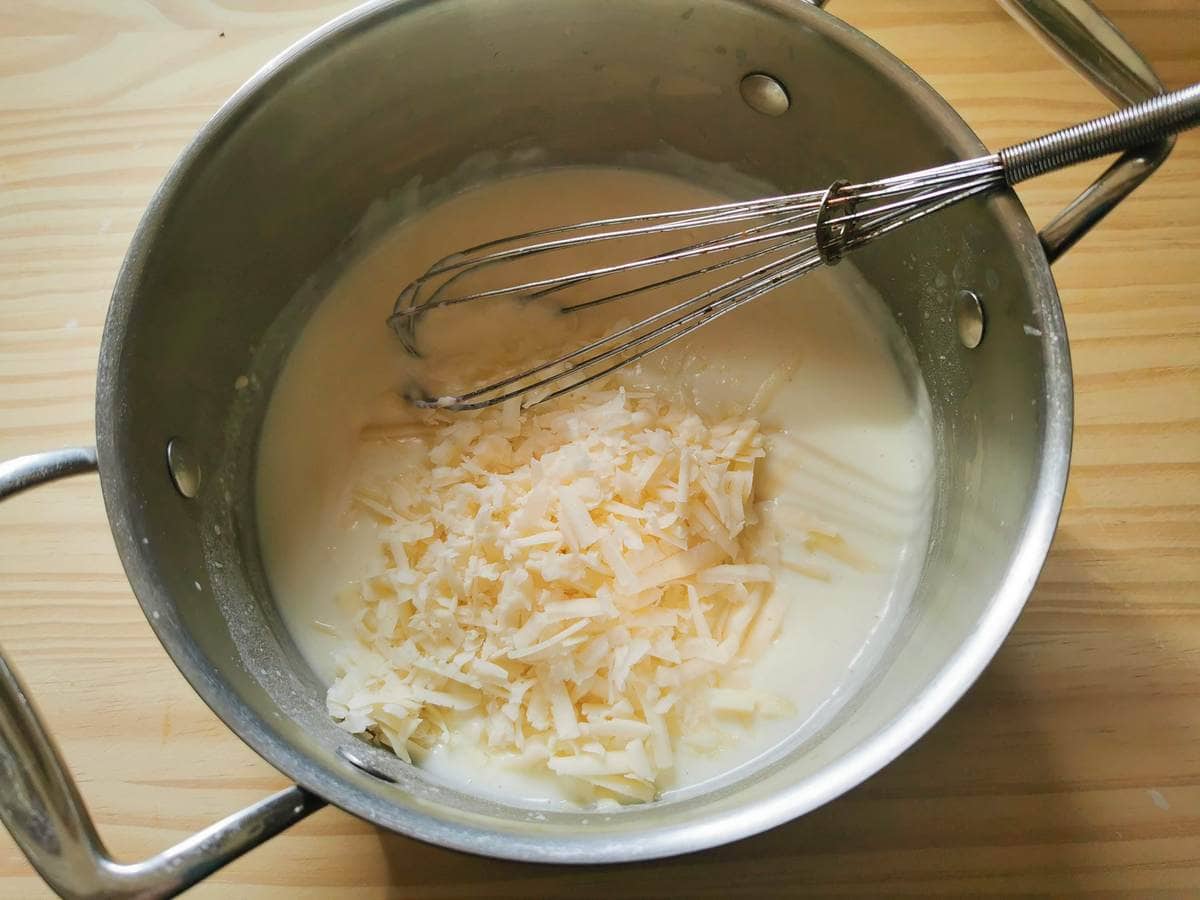 Grated Montasio cheese in pan with béchamel sauce.