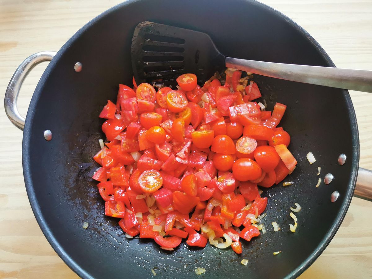Fresh tomatoes in large skillet with cooked red pepper and onion.