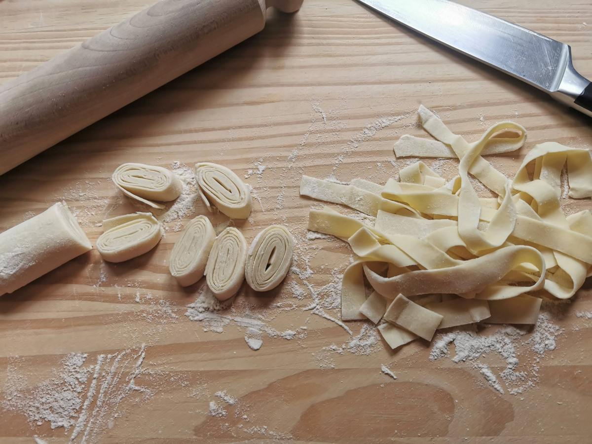 Rolled up pasta sheet cut into ribbons on wood work top.