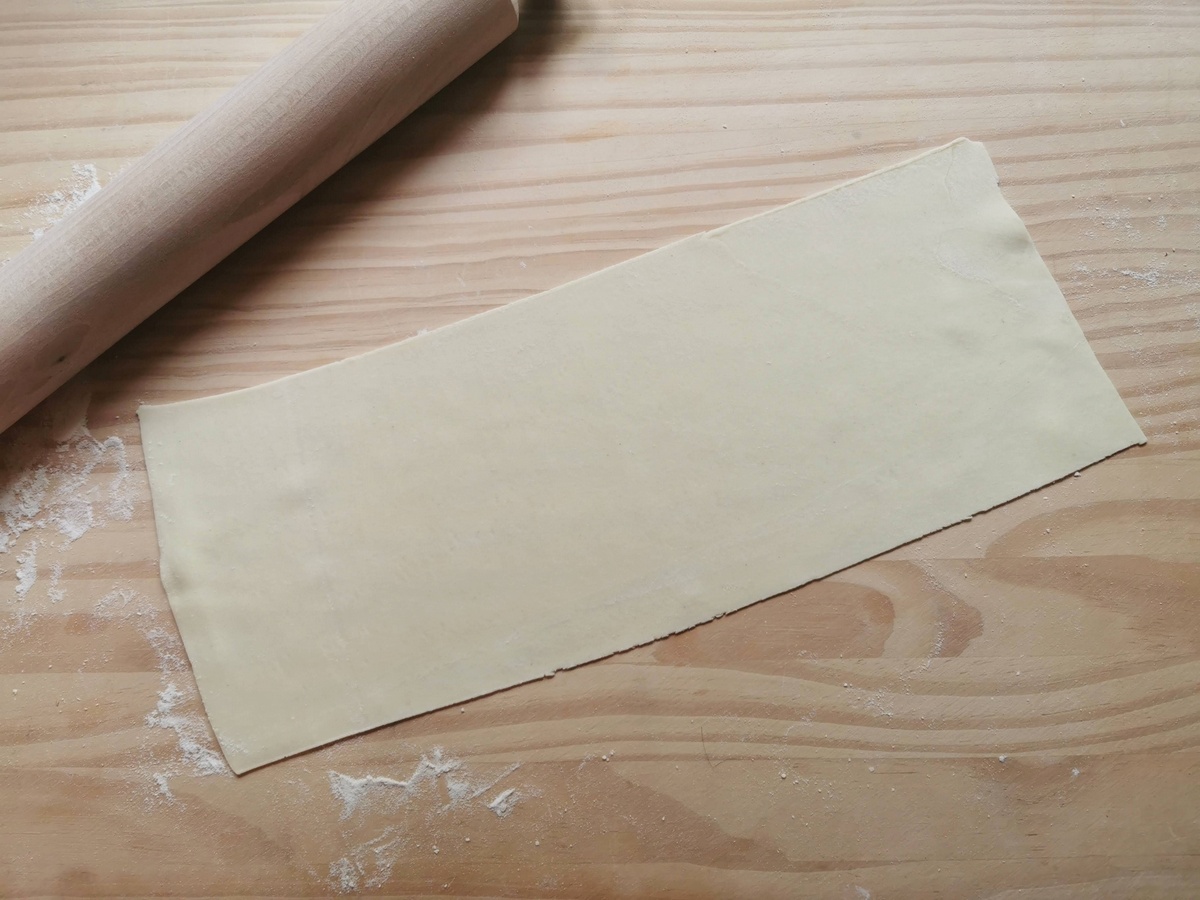 Ready rolled out rectangular eggless pasta sheet on wood work top.
