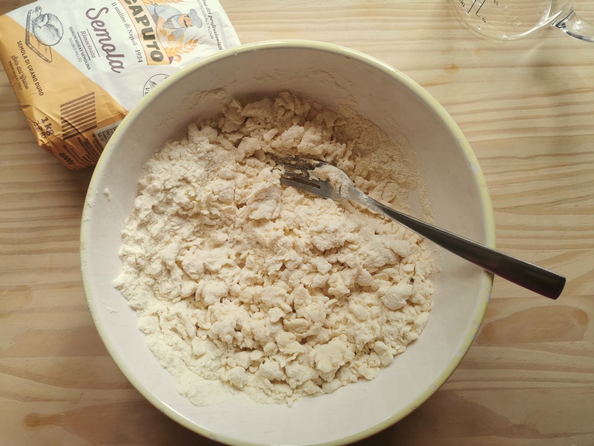 Semolina flour and water mixed together in bowl with a fork.
