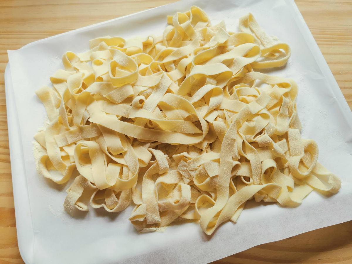 Ready to cook eggless vegan tagliatelle on baking paper covered tray.