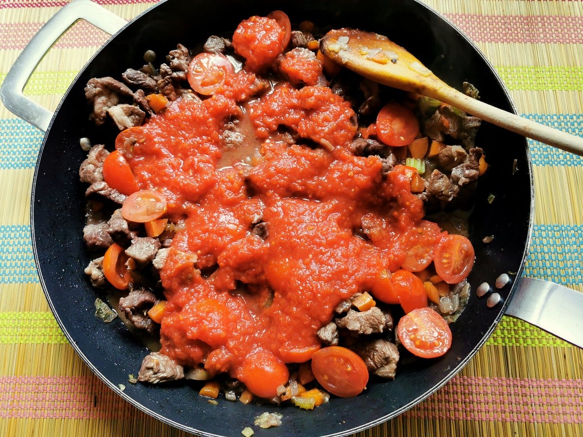 tomato passata (purée) in skillet with lamb, vegetables and cherry tomatoes.