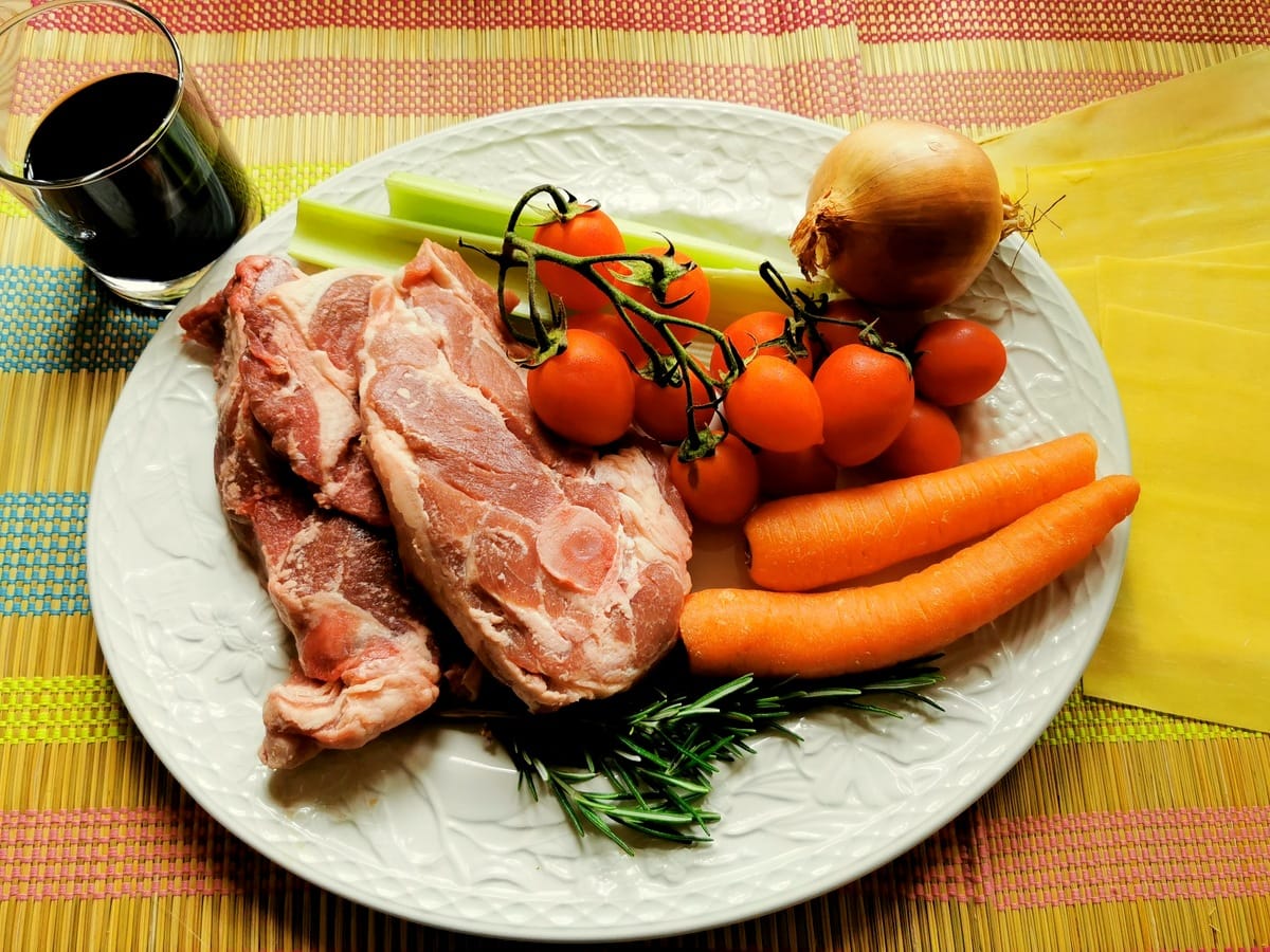 ingredients for lamb ragu on large white plate