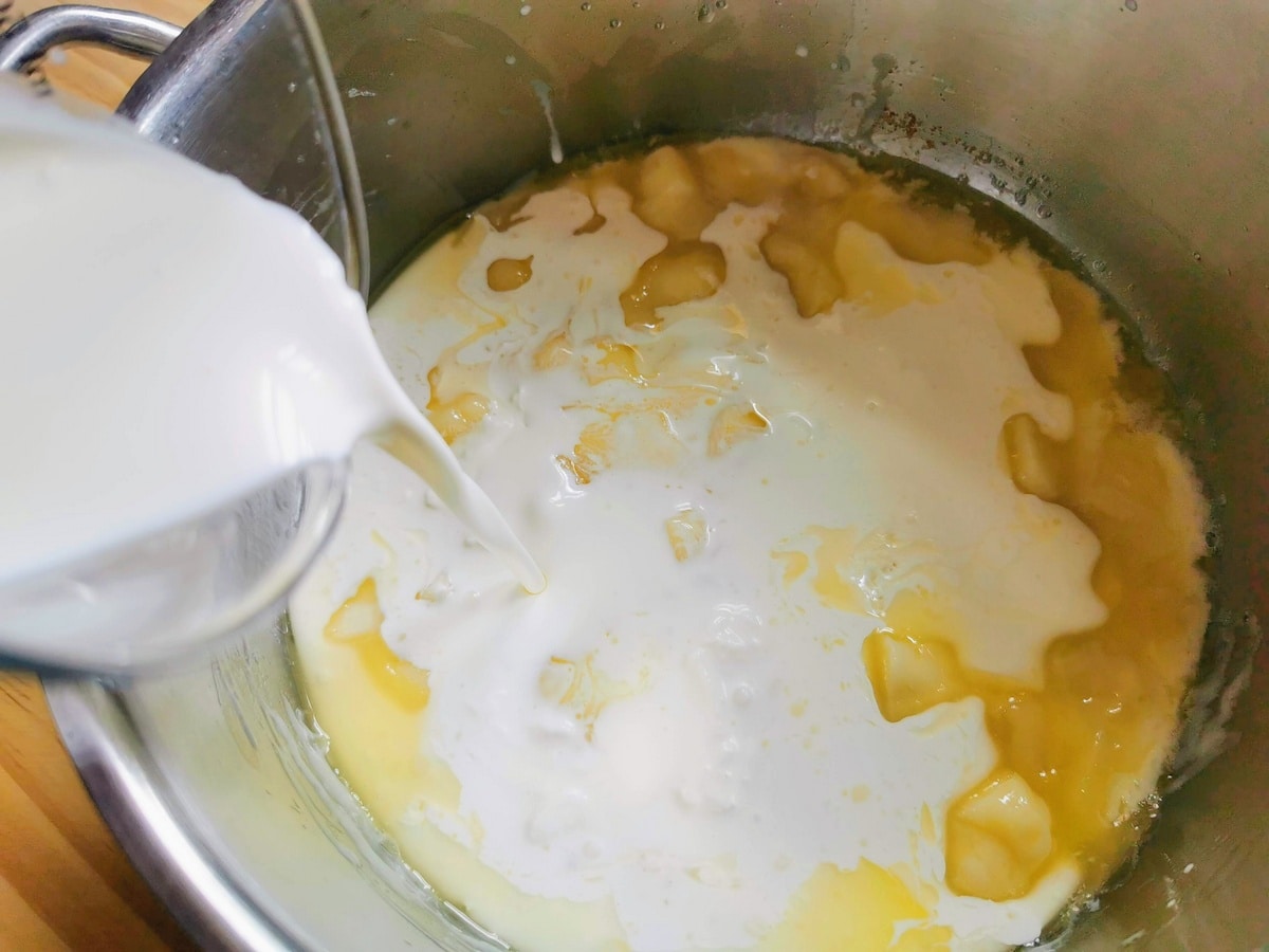 Cream being added to melted cheese and butter in deep pan.