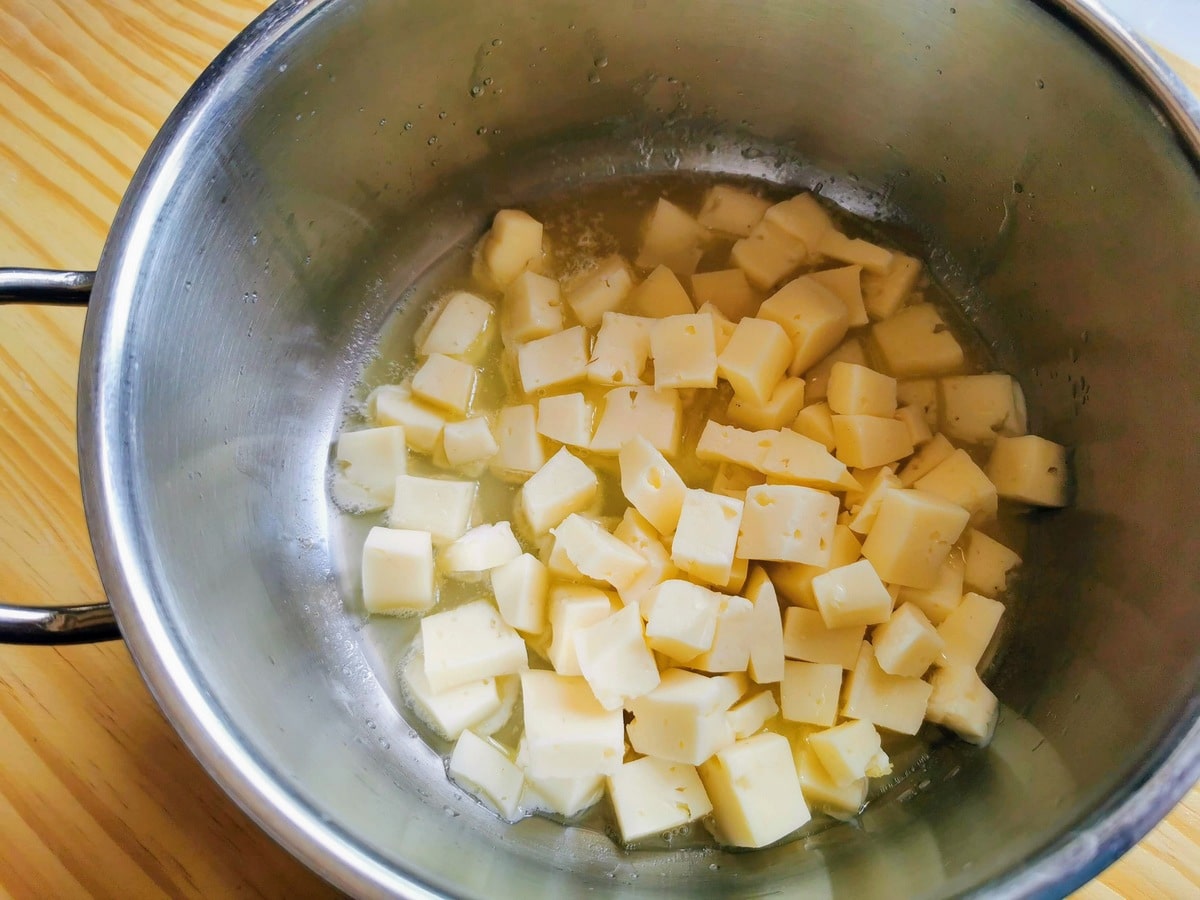 Cubes of Raschera cheese in deep pan with melted butter.