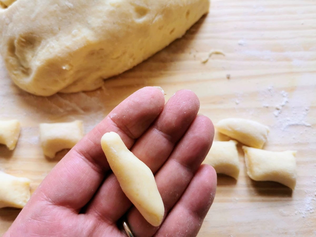 One piece of spindle-shaped gnocchi della Val Varaita held in a woman's hand.