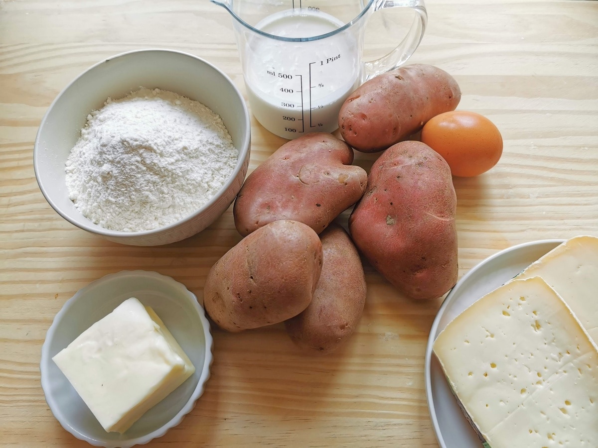 Ingredients for Italian gnocchi della Val Variata on wood work surface. Potatoes, flour, butter, cream, cheese and an egg.