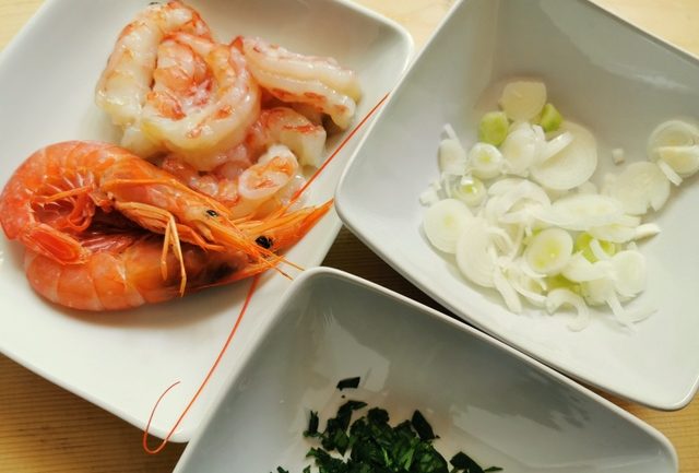 chopped spring onions in white bowl. Chopped parsley in white bowl. Prepared prawns in white bowl