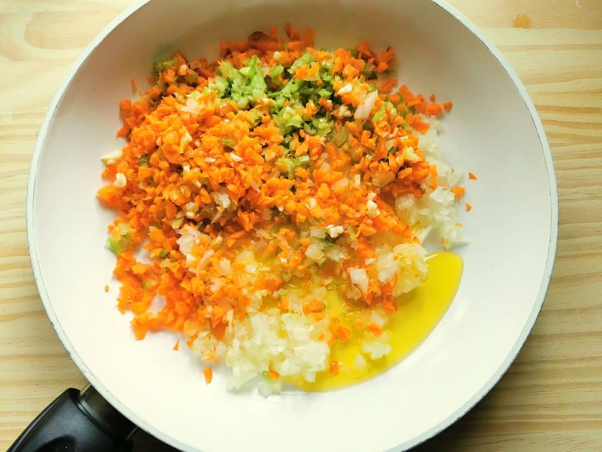 Finely chopped onions, garlic, celery and carrots in frying pan with olive oil.