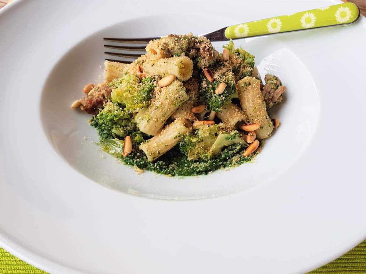 A portion of Sicilian broccoli pasta with sausage and chard in a white bowl