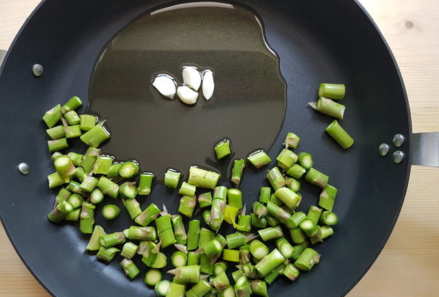 cut asparagus pieces and fresh garlic in frying pan