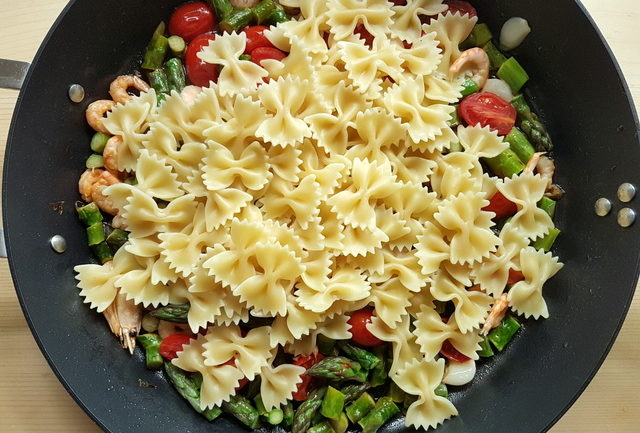 cooked farfalle pasta in frying pan with sauce ingredients