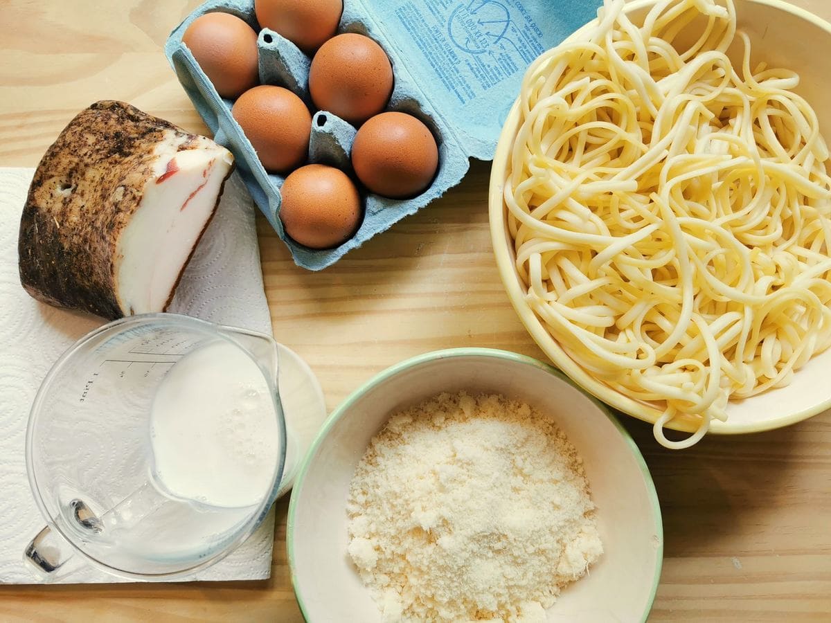 Ingredients for spaghetti carbonara frittata on wood worktop.