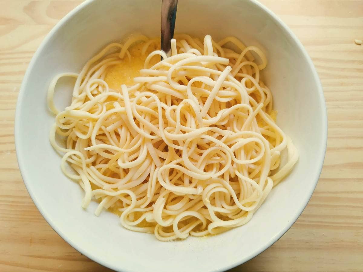 Cooked spaghetti in white bowl with frittata egg mixture.