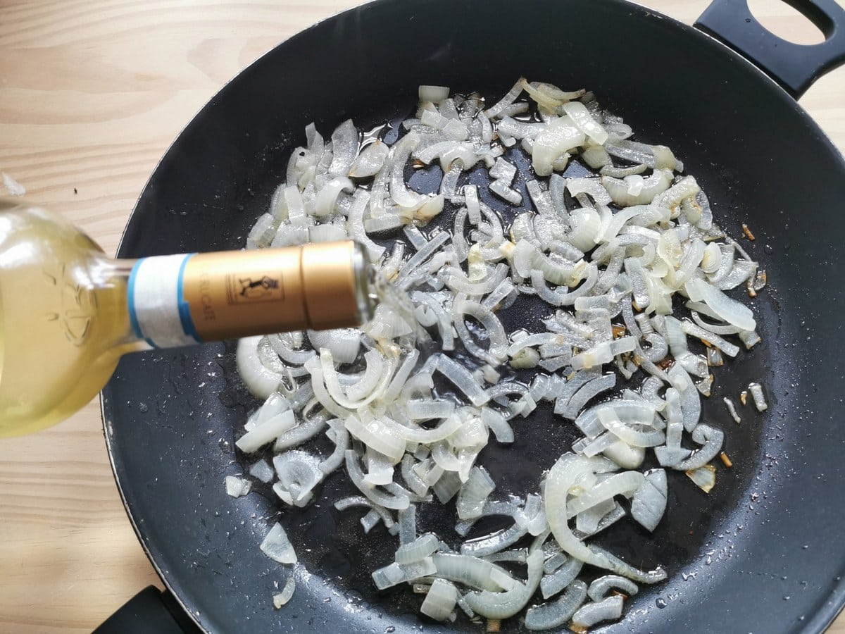 White onions cooking in deep frying pan.