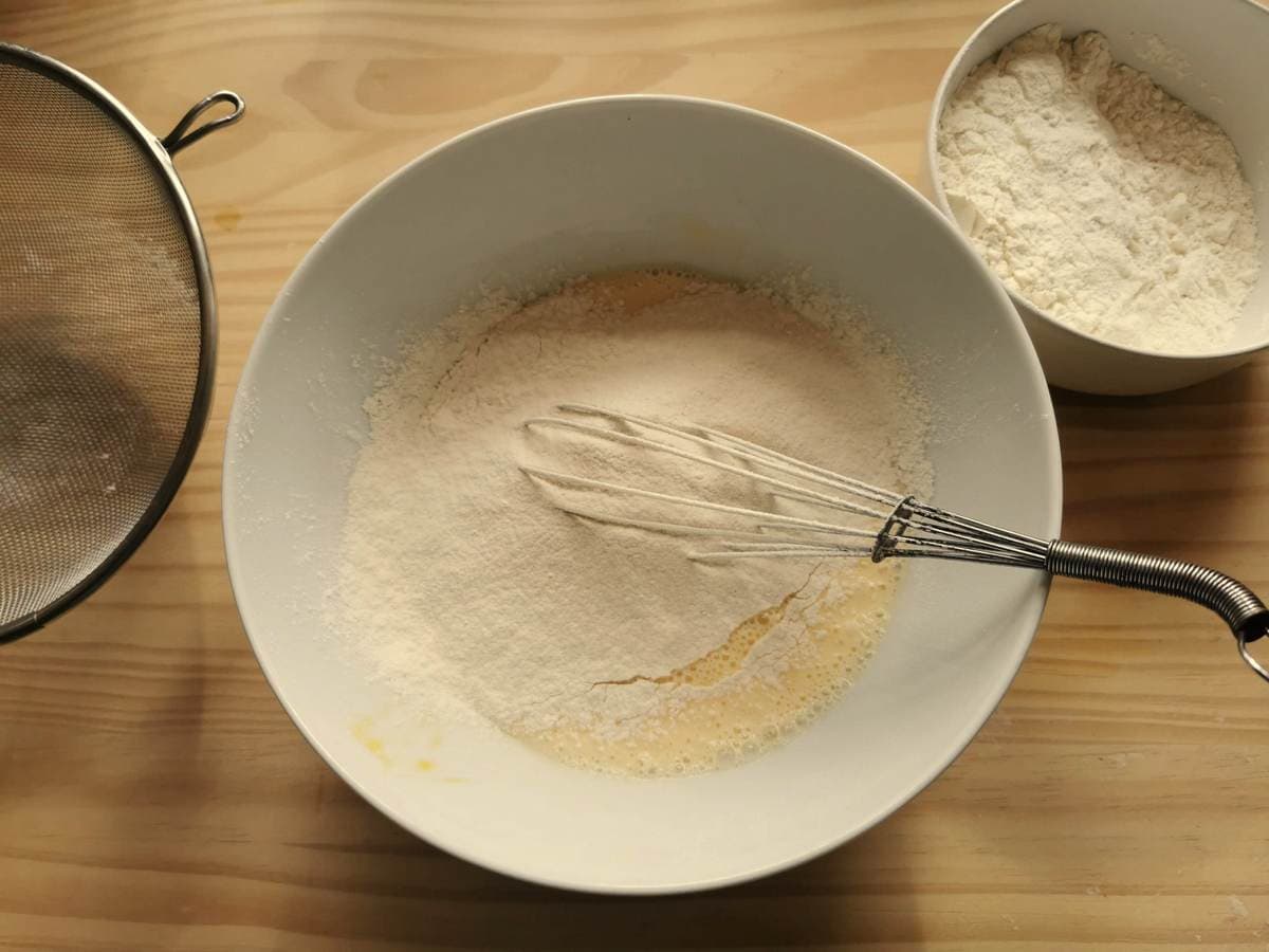 White flour added to bowl with beaten egg and milk.