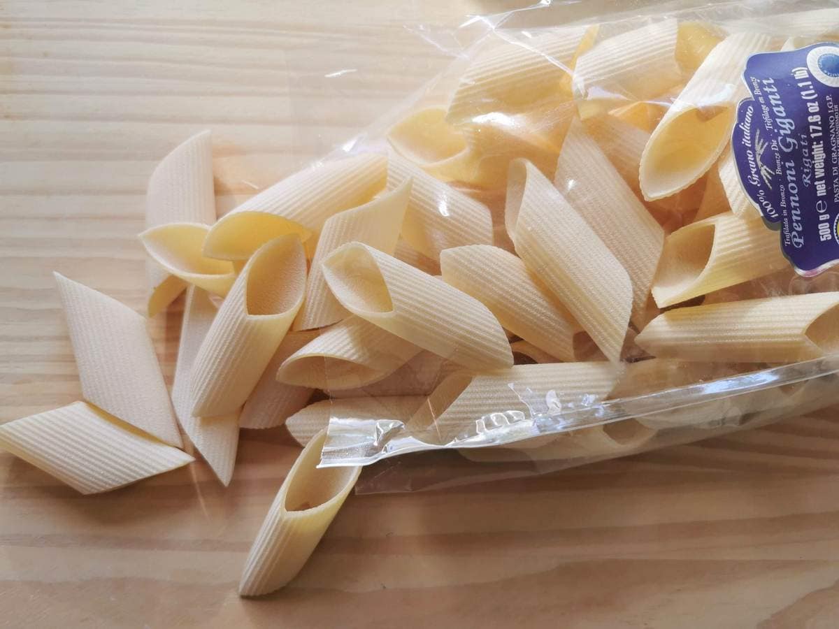 Large grrooved penne (pennoni giganti) on wood work surface.