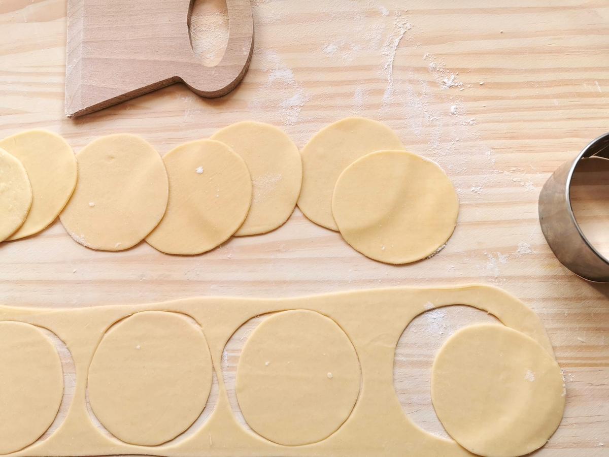 Dough circles cut from pasta sheet on wooden board