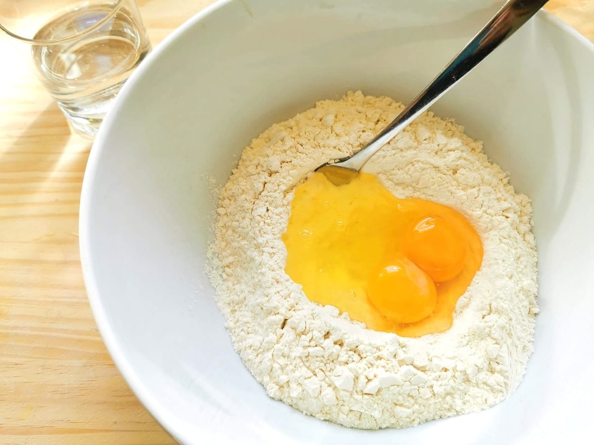 Soft wheat flour, eggs and water in a white bowl