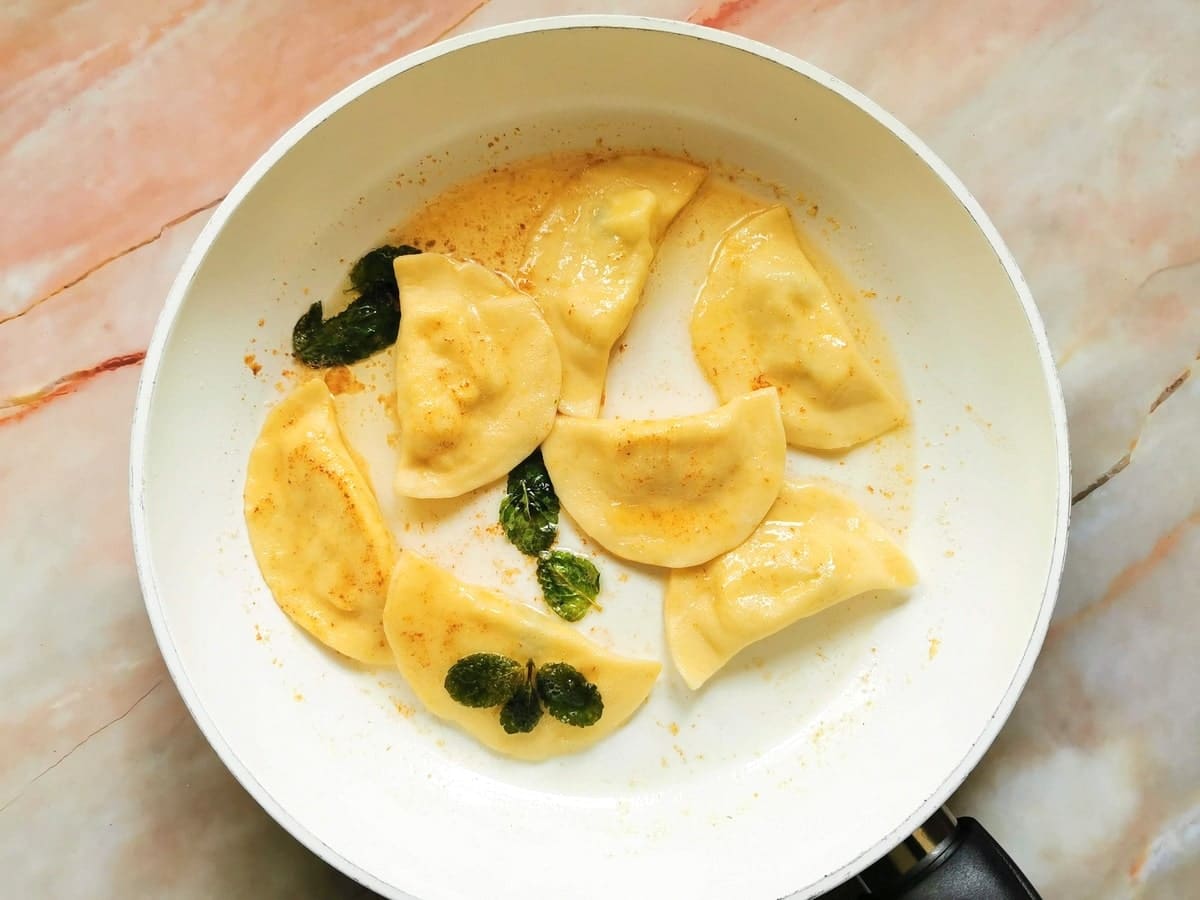 Cooked ravioli in pan with melted butter and mint leaves