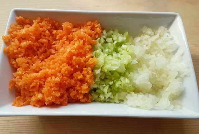 finely chopped onion, celery and carrots in a white bowl