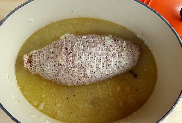 Rolled veal shoulder cooking in Dutch oven