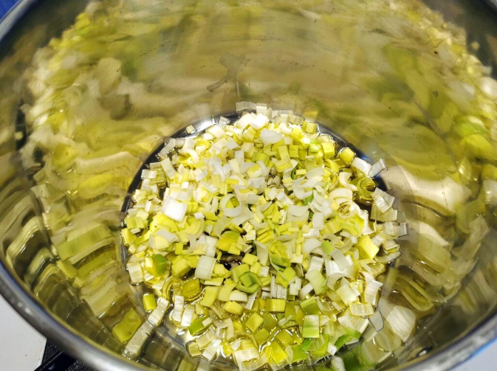 sliced leeks cooking in olive oil in large soup pot.