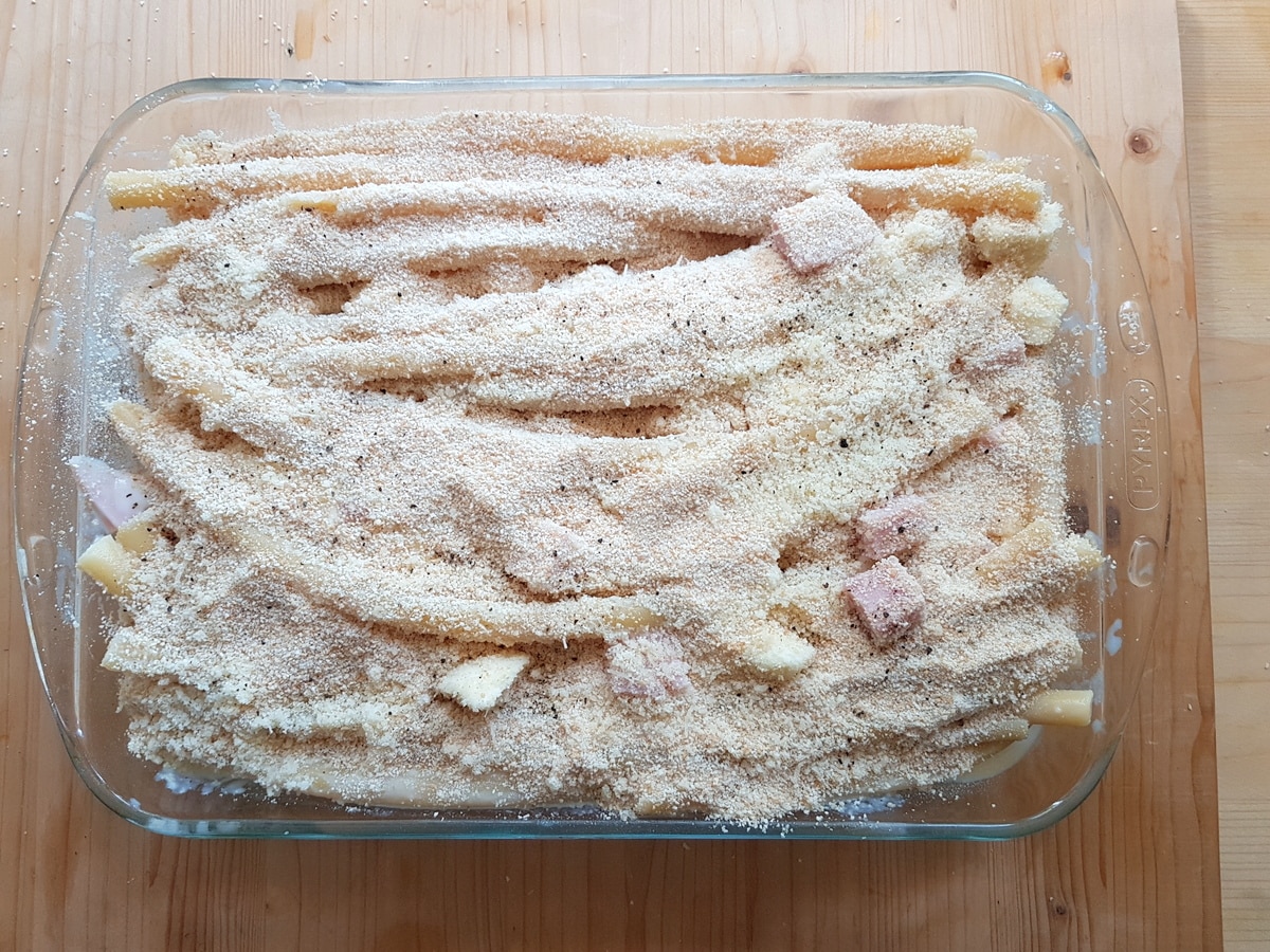 zitoni pasta in oven dish covered with parmigiano and breadcrumbs