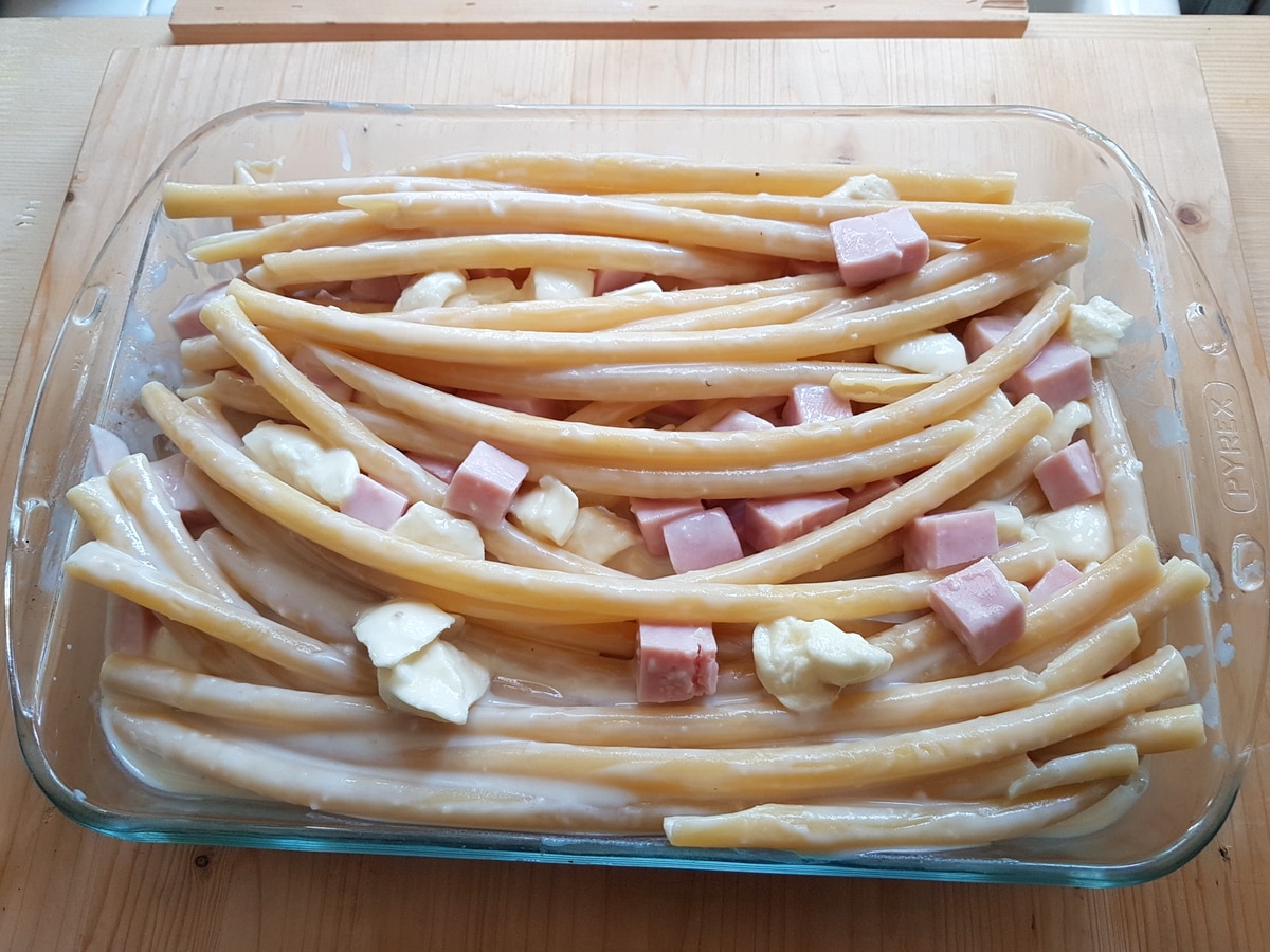 cooked ziti pasta in oven dish with béchamel, ham and mozzarella