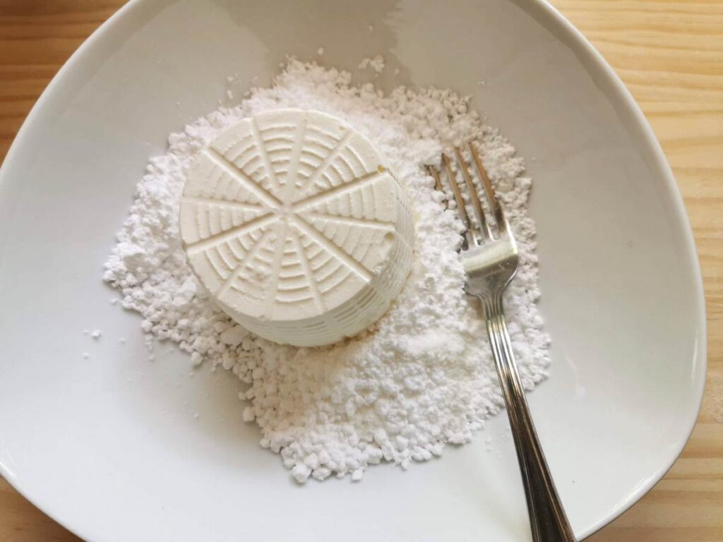 fresh ricotta and icing sugar in white bowl