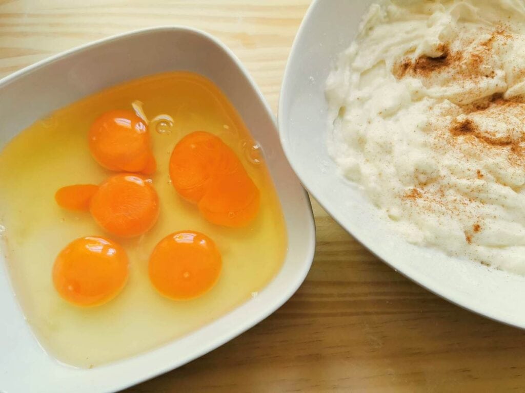 Eggs in white bowl and creamed ricotta with cinnamon in second white bowl