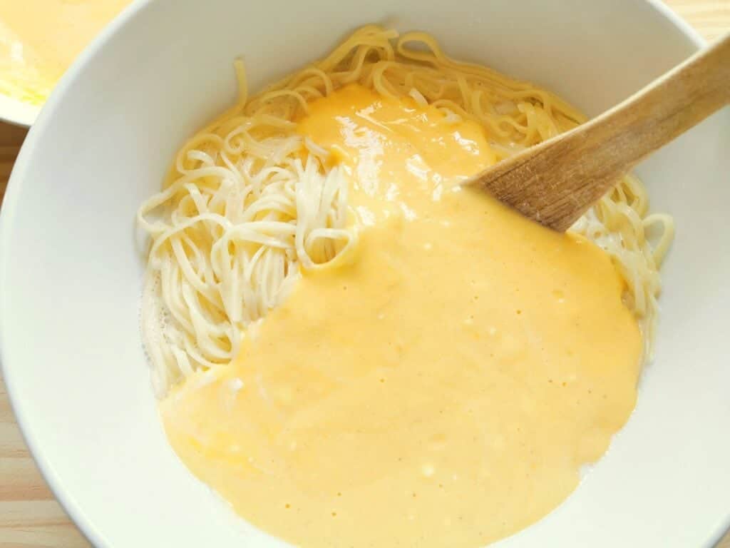 Ricotta and egg mixture added to the pasta and milk in white bowl